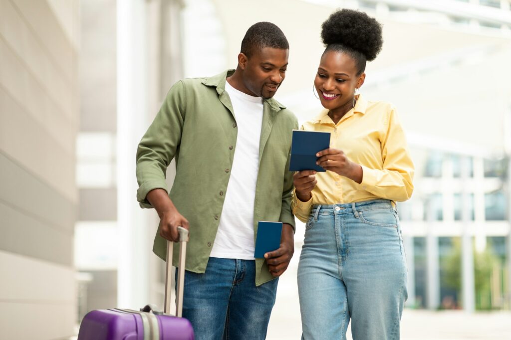 Cheerful African American Couple Holding Passports Standing In Airport Indoors