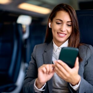 Happy businesswoman texting on mobile phone while traveling by train.